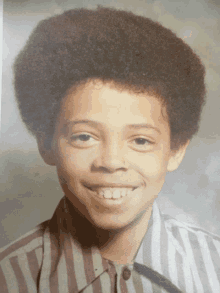 a young boy with a striped shirt on smiles for the camera