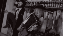 a man and a woman are playing an accordion and the woman is wearing a cowboy hat