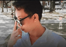 a man wearing sunglasses holds his finger to his forehead in a blurry photo