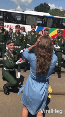 a woman taking a picture of a man in a military uniform with a bus in the background that says apal