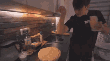 a man is standing in a kitchen cooking a pie .