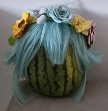 a watermelon with a blue wig and flowers on top