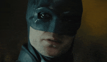 a man in a batman mask looks at the camera