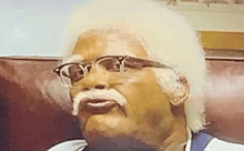a man with glasses and a mustache is sitting on a couch ..