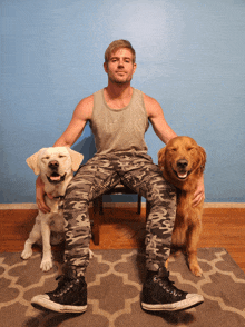 a man wearing a hurley tank top sits on a chair holding two dogs