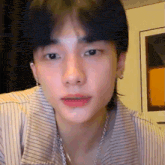 a close up of a person 's face wearing a striped shirt and a necklace .