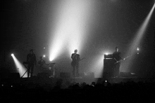 a black and white photo of a group of people playing instruments on a stage .