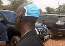 a man with a mask on his head is standing next to a car .