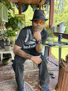 a man wearing a black reebok shirt sits on a bench