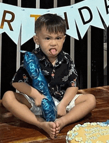 a little boy is sitting on the floor holding a blue balloon .