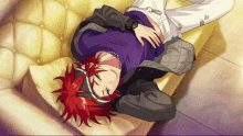 a man with red hair is laying on a yellow couch .