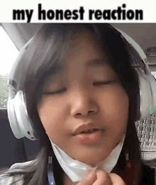 a young girl wearing headphones and a mask is making a face .