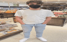 a man wearing a mask stands in front of a winery section of a grocery store