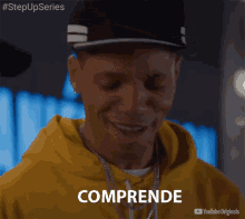 a man wearing a hat and a yellow hoodie has the word comprehende written on his face