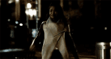 a woman is running down a street at night .