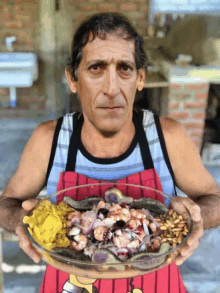 a man in a red apron holds a bowl of food