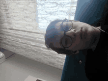 a person wearing glasses and headphones is laying on a couch in front of a window