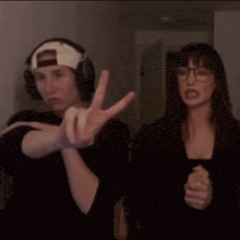 a man and a woman are standing next to each other and the man is wearing headphones and the woman is wearing glasses