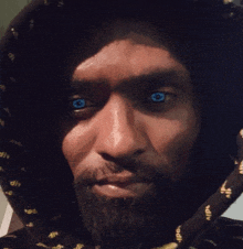 a man with blue eyes and a beard wearing a black hoodie