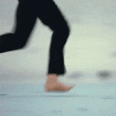 a blurry picture of a person 's legs walking on a blue surface