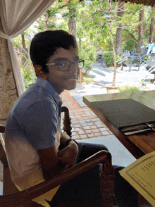 a boy with glasses sits at a table with a menu on it