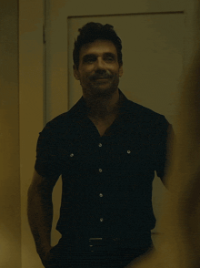 a man in a black shirt stands in front of a white door