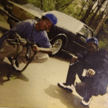 a man in a blue hat is kneeling next to another man with a gun