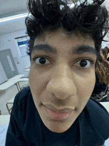 a young man with curly hair looks at the camera with a funny face