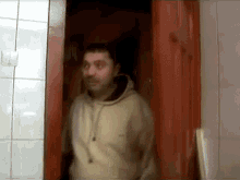 a man wearing a nike sweatshirt stands in a doorway