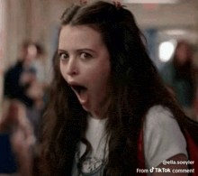 a young woman is making a surprised face with her mouth open .
