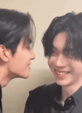 two young men are kissing each other and smiling .