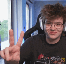 a young man wearing glasses and a shirt that says st. chris is giving the peace sign