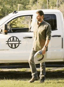 a man holding a cowboy hat stands in front of a white truck that says 500 hd on the side