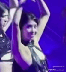 a woman is dancing with her arms in the air on a stage .