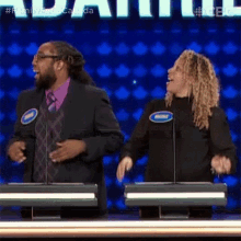 a man and a woman are dancing in front of microphones on a television show called family feud canada .