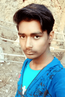 a young man wearing a blue shirt with the letter t on it poses for a picture