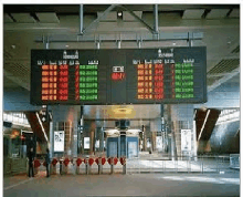 a large sign hanging from the ceiling at an airport shows the time and departures for flights .