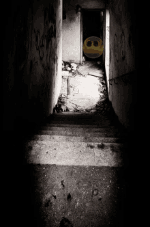 a black and white photo of a dark hallway with a yellow smiley face in the middle