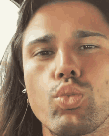 a close up of a man 's face with his lips blowing a kiss