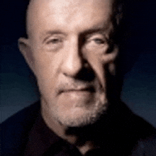 a close up of a man 's face with a beard and a dark background .