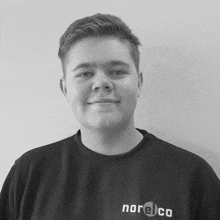 a black and white photo of a young man wearing a norelco shirt