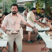 a man is standing in front of a crowd of people at a buffet table holding a tray of food .