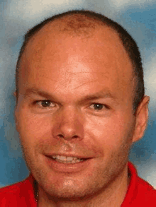 a close up of a man 's face with a red shirt on .