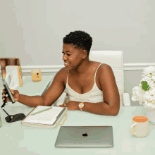 a woman is sitting at a desk with an apple laptop