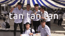 a group of young men are posing for a picture under an umbrella with the words tan tan tan below them