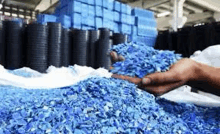 a person is holding a pile of blue plastic waste in a factory .