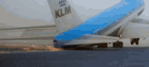 a blue and white klm airplane is sitting on the runway