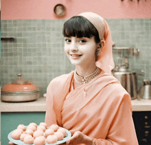 a woman in a pink sari holds a plate of food