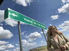 a woman stands in front of a green sign that says home on the range