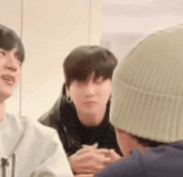 a group of young men are sitting around a table and talking to each other .